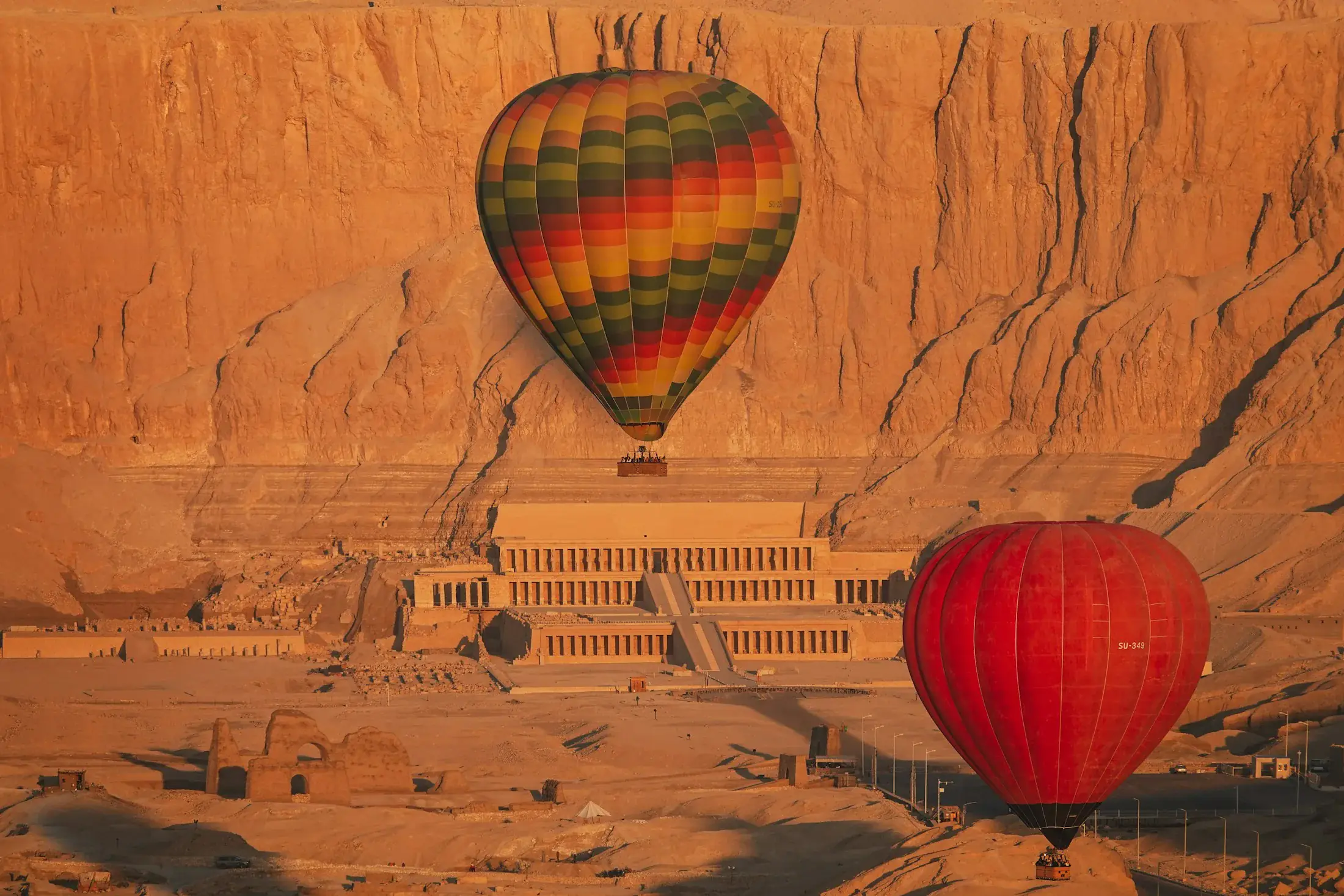 Desert hills and Hatshepsut’s temple in Luxor, with hot-air balloons above
